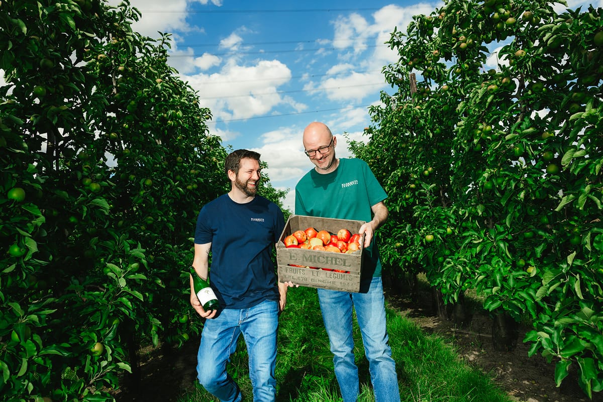 De twee makers van Klokhuys Fermenten in de boomgaard, met een kist vol geplukte appels.